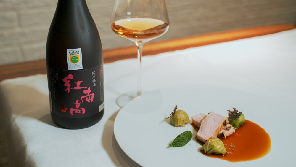 bouteille de umeshu beninanko avec un verre rempli et un plat avec de la nourriture