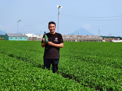 brasseur de chiran jozo avec bouteille shochu dans un champ de thé